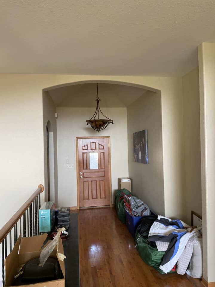 Existing foyer before renovation with arched entry, pendant light fixture, and wood front door